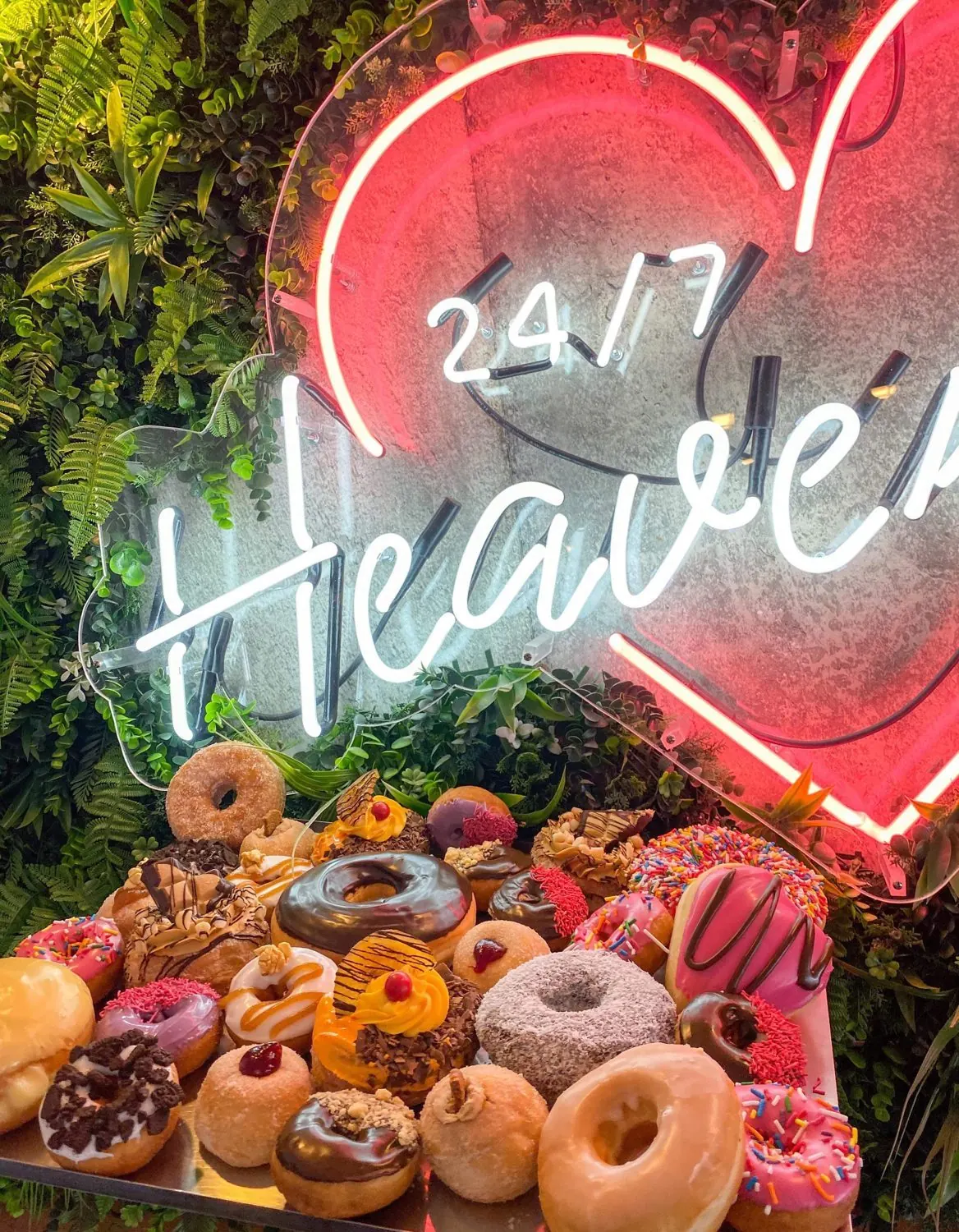 The 24/7 Heaven neon heart above a spread of iced donuts.