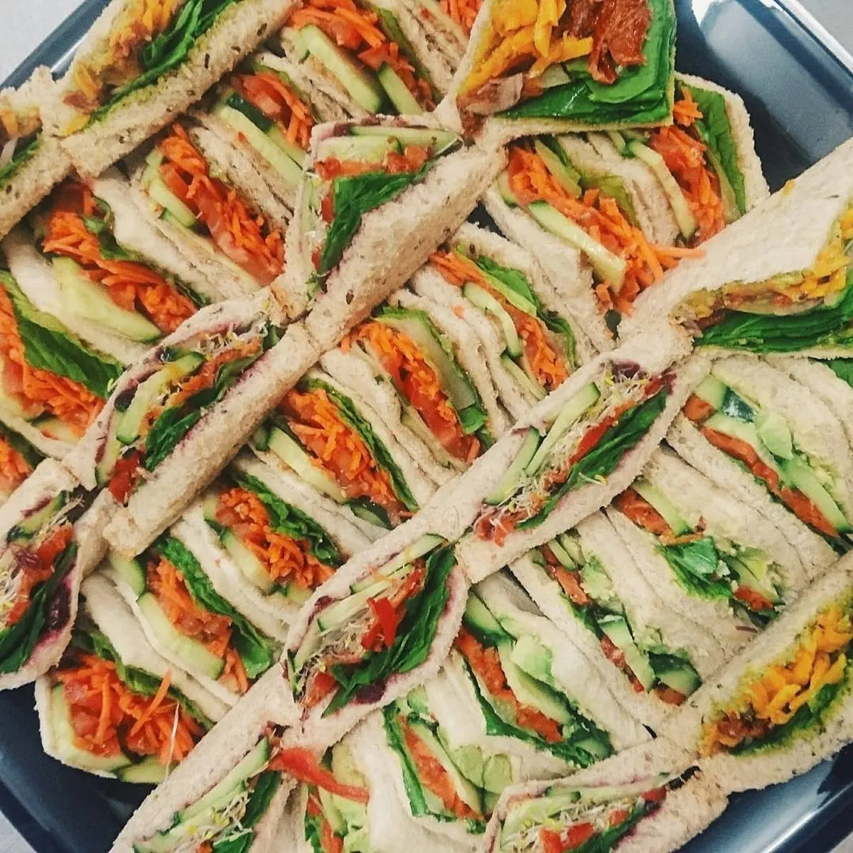 A platter of cut sandwiches arranged in rows.