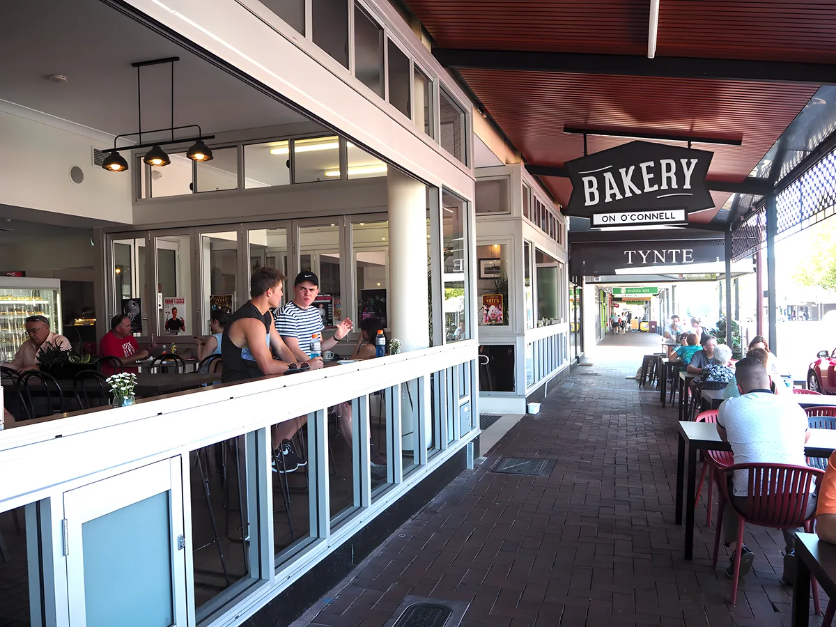 The verandah at Bakery on O'Connell, with customers seated under the hanging sign.